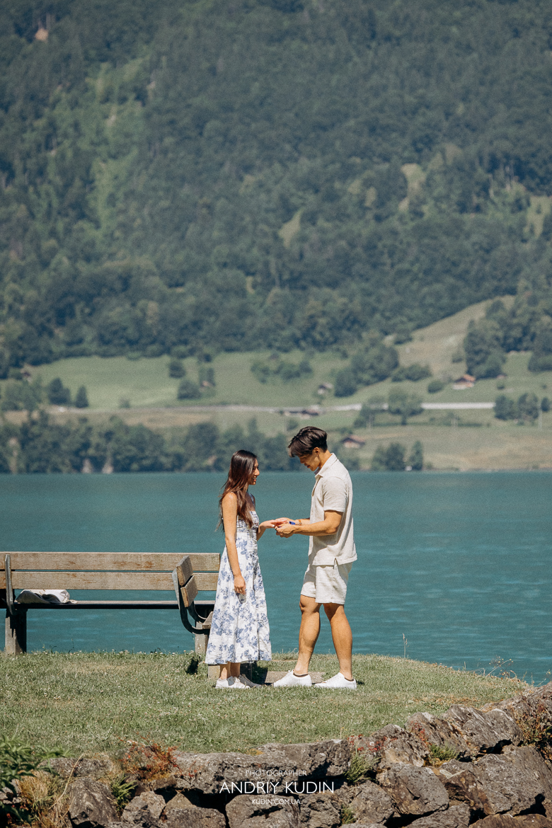 Couple proposing on Iseltwald wooden pier with Lake Brienz view. Marriage proposal photoshoot in Iseltwald, Switzerland.