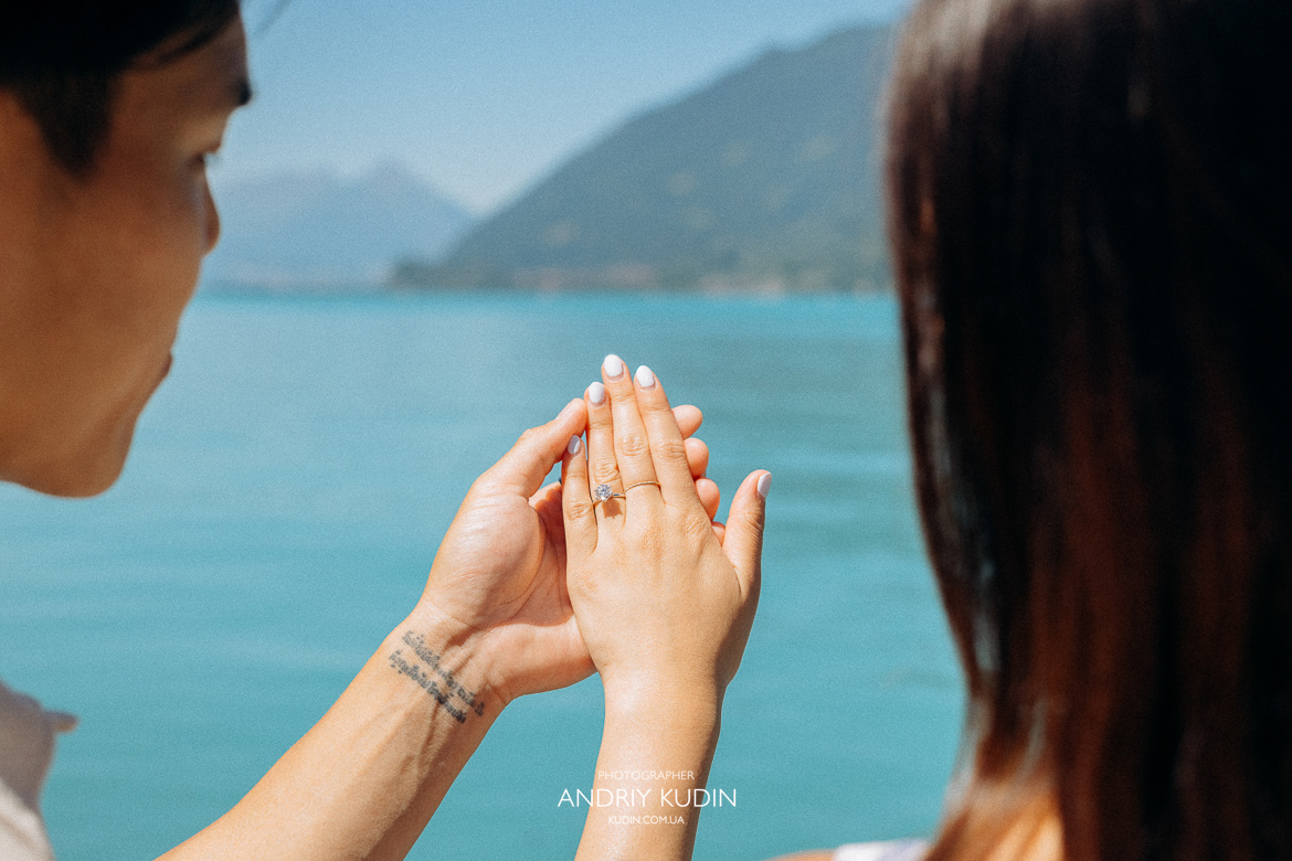 Couple proposing on Iseltwald wooden pier with Lake Brienz view. Marriage proposal photoshoot in Iseltwald, Switzerland.