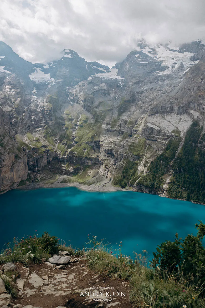 Wide alpine view of Lake Oeschinen surrounded by cliffs and clouds Wide alpine view of Lake Oeschinen surrounded by cliffs and clouds