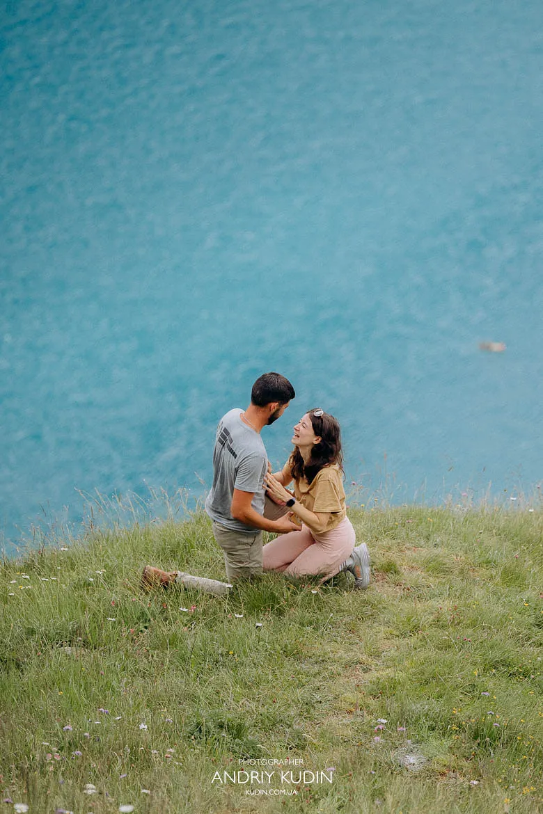 Tender kneeling moment at Lake Oeschinen proposal, with bright alpine colors and natural marriage proposal photography in Switzerland. Tender kneeling moment at Lake Oeschinen proposal, with bright alpine colors and natural marriage proposal photography in Switzerland.