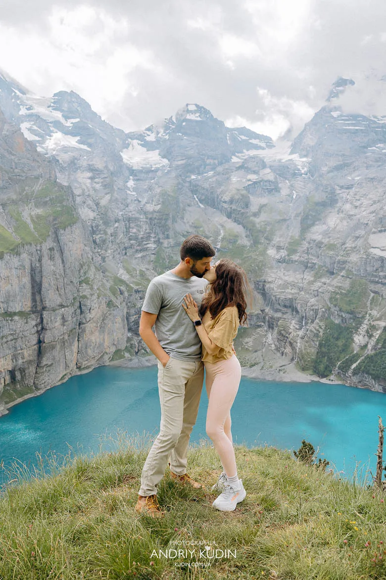 Lake Oeschinen proposal moment with a couple overlooking the turquoise lake and mountains Lake Oeschinen proposal moment with a couple overlooking the turquoise lake and mountains