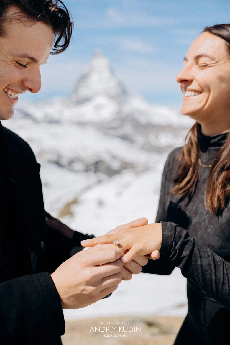 Man placing diamond ring on finger during matterhorn proposal by proposal switzerland