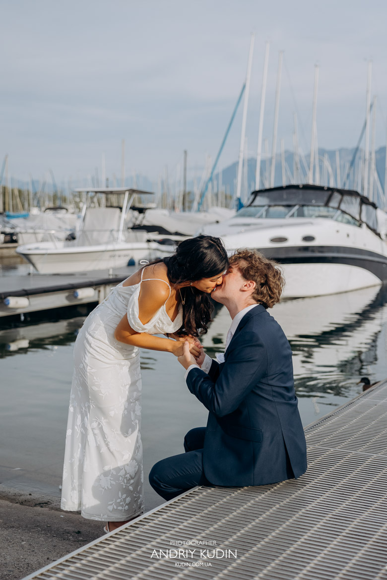 Lausanne wedding photographer captures couple kissing by Lake Geneva at sunset with Alps in background.