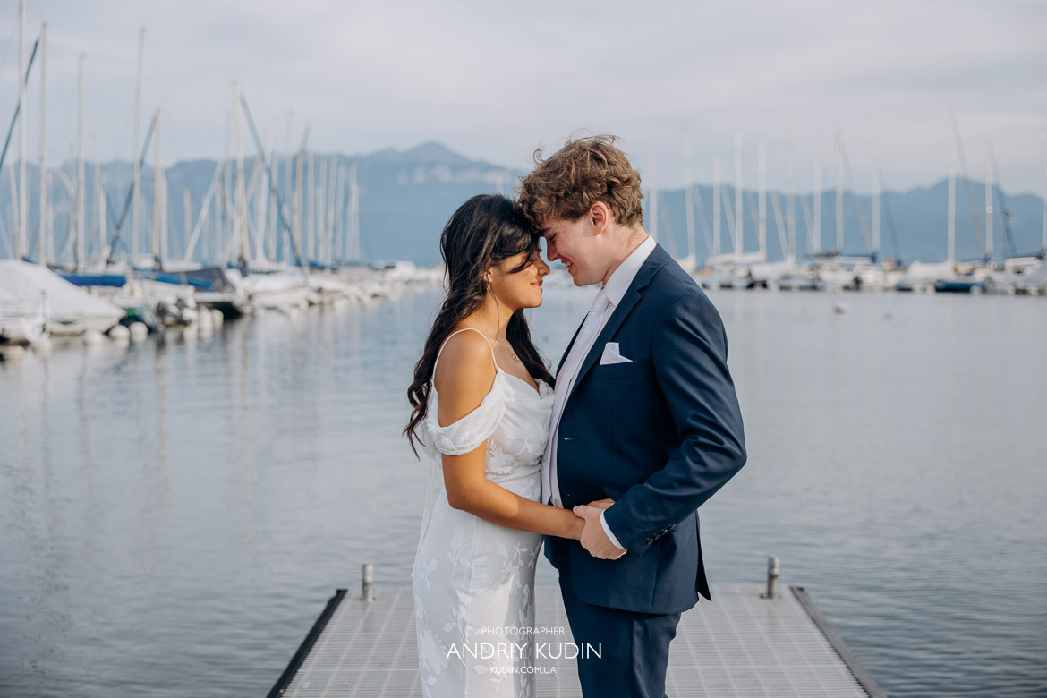 Lausanne wedding photographer captures couple kissing by Lake Geneva at sunset with Alps in background.
