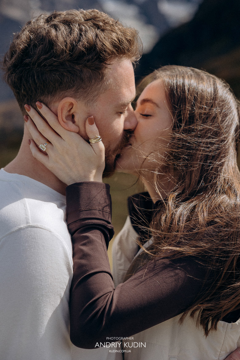 Romantic engagement kiss in Swiss mountains