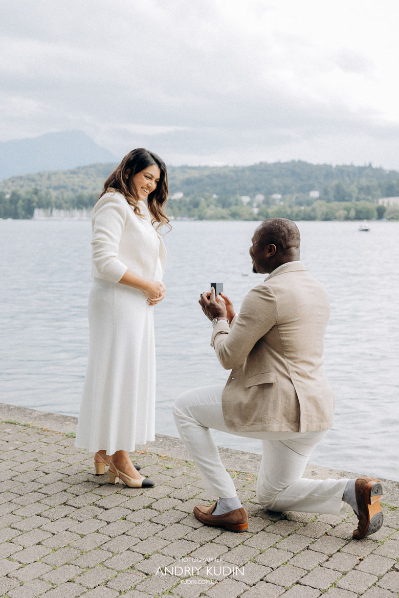 propose in zurich, zurich proposal, propose in switzerland, Man kneeling with engagement ring beside swans on Lake Zurich