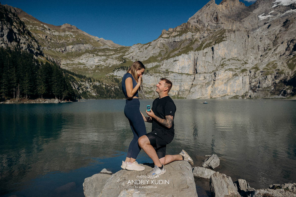 Engagement scene at Lake Oeschinen featuring a couple in love as he offers her a Tiffany diamond ring.