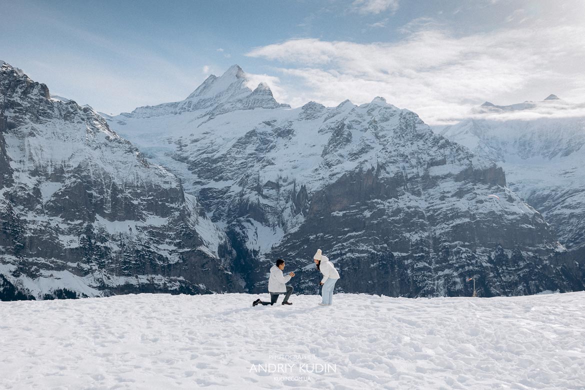 Couple proposing in front of massive white mountains in Grindelwald