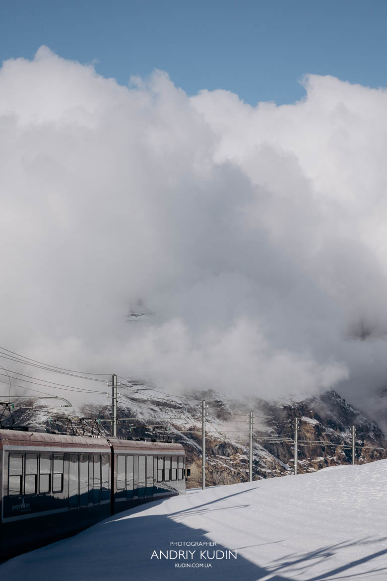 Red Gornergrat Bahn cogwheel train climbing the snowy Alps.