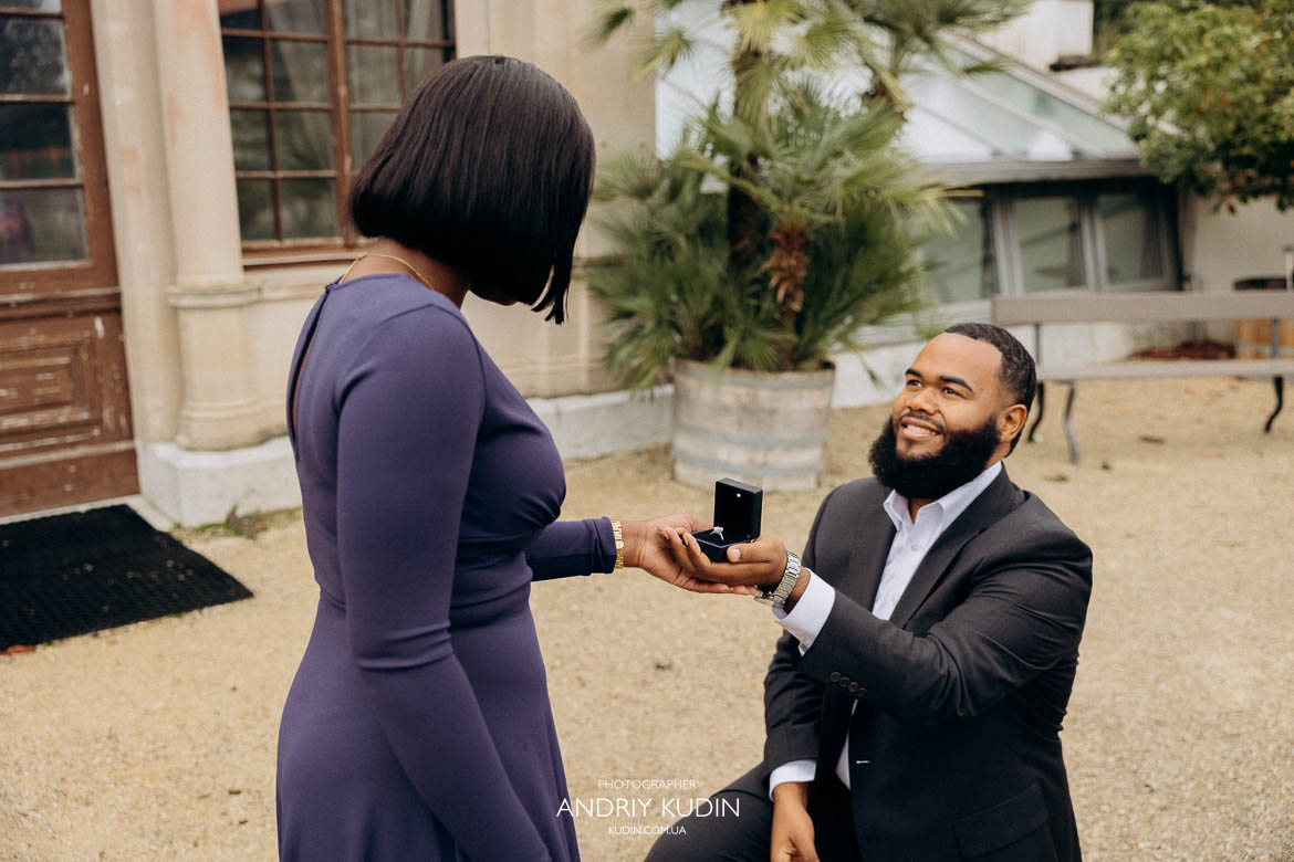 Man presenting engagement ring box while kneeling during proposal in Zurich