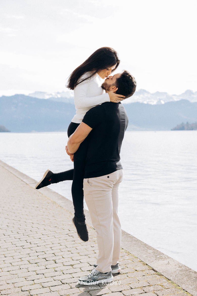 Groom lifting his fiancée in his arms after romantic proposal in Luzern by Lake Lucerne