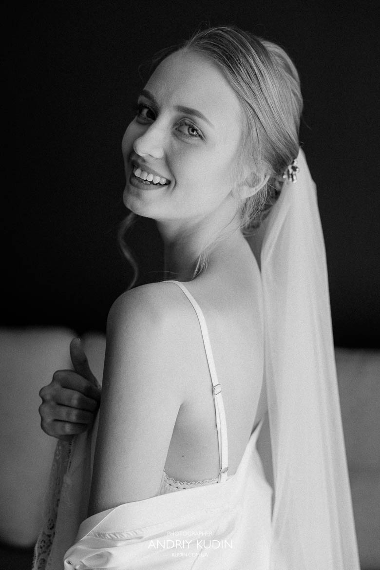 Braut hält ihr Hochzeitskleid im Hotelzimmer