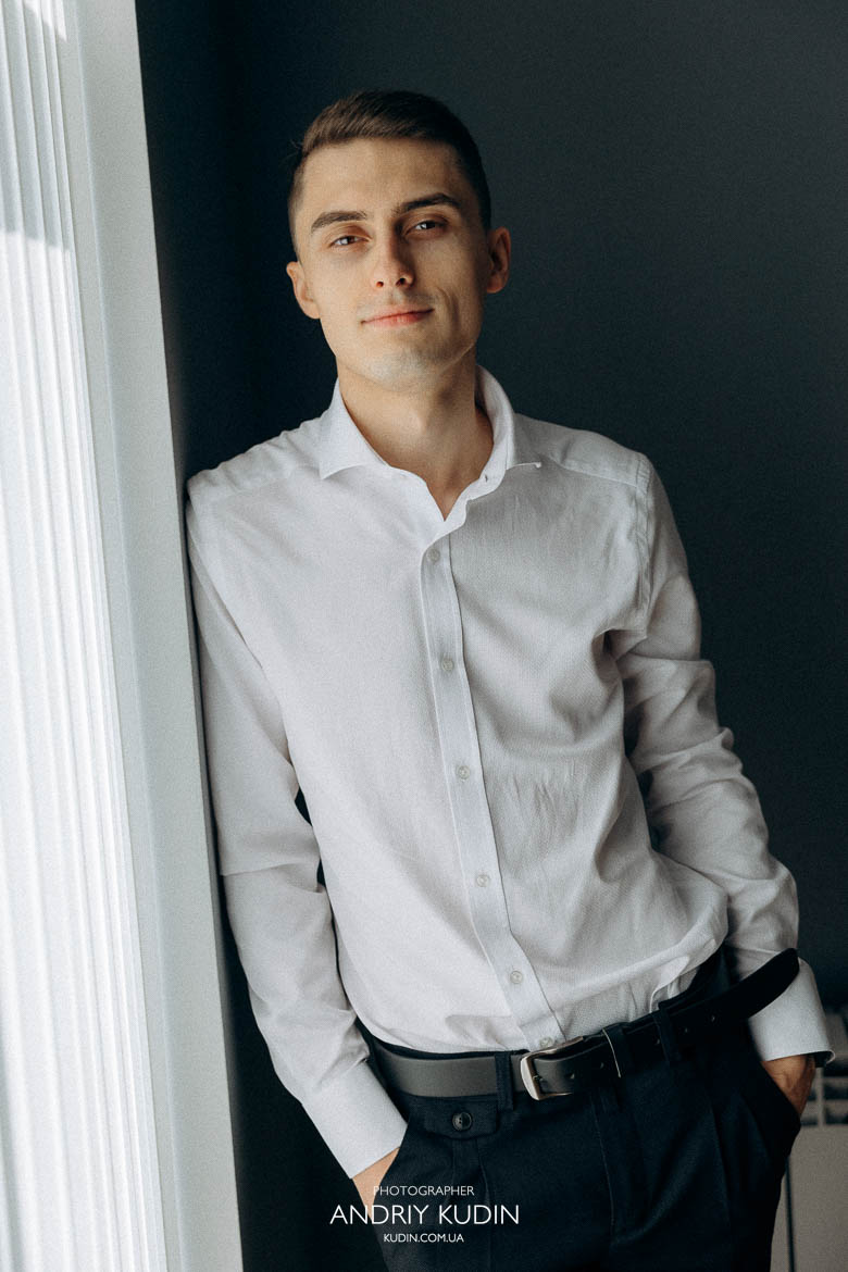 Bräutigam richtet seine Fliege im Hotelzimmer Bräutigam mit Boutonniere am Anzug