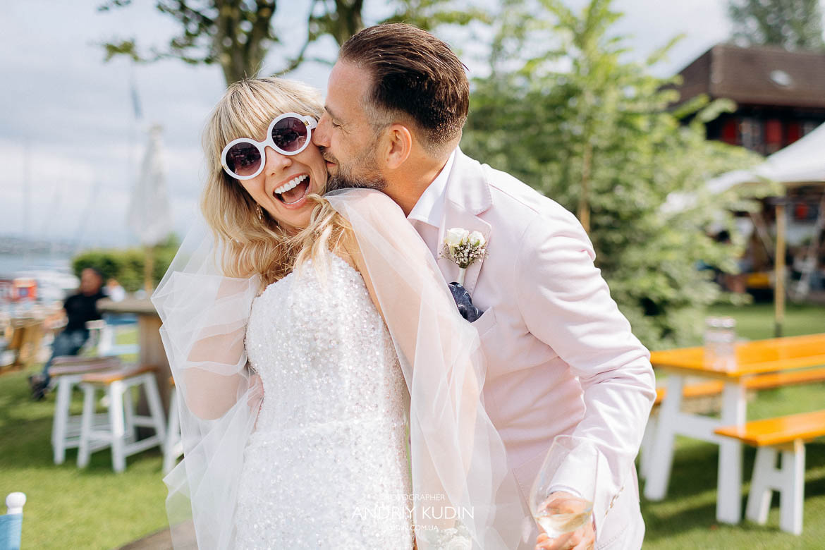Elegante Braut mit fließendem Schleier und Bräutigam am Zürichsee bei einer Hochzeit in Zürich, Intime Hochzeitsfotos eines verliebten Paares am Zürichsee in Zürich Schweiz