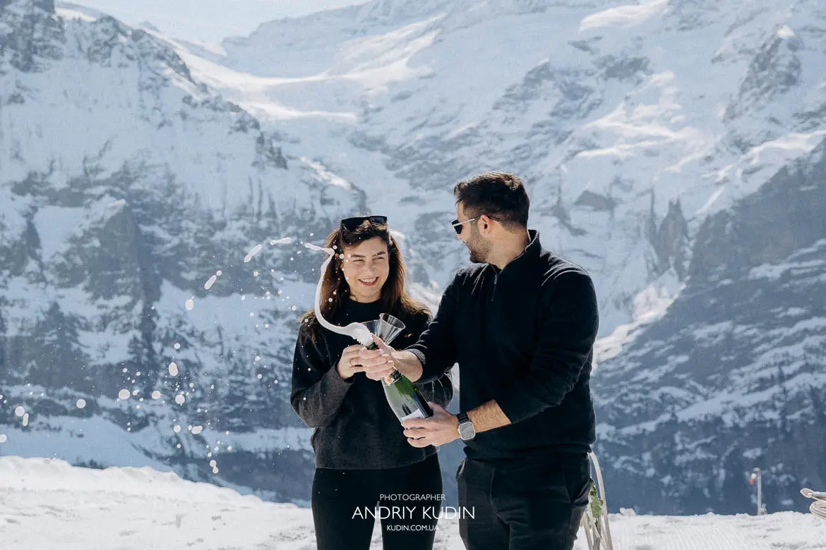 couple opening champagne Swiss Alps, champagne celebration after proposal