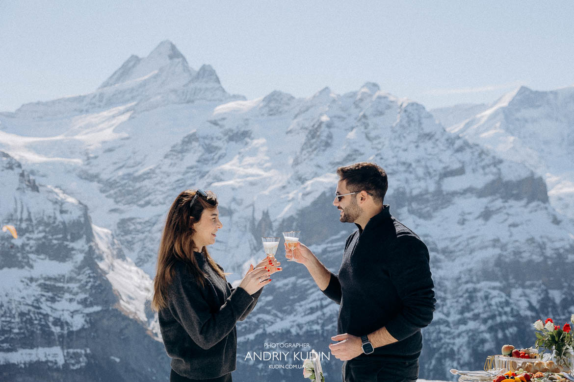 couple celebrating with champagne Alps, joyful engagement celebration Switzerland