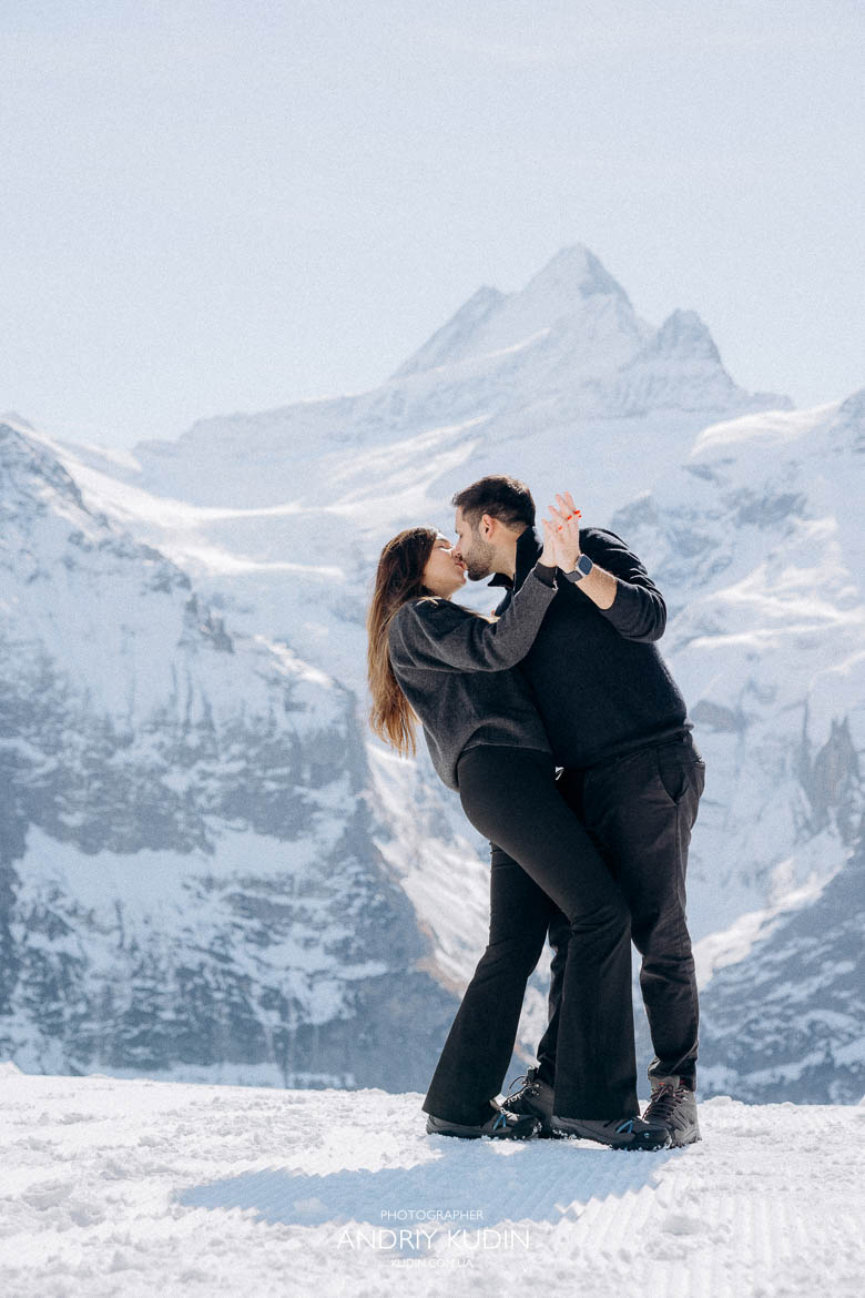 happy couple hugging snowy mountains, romantic kiss engagement Switzerland