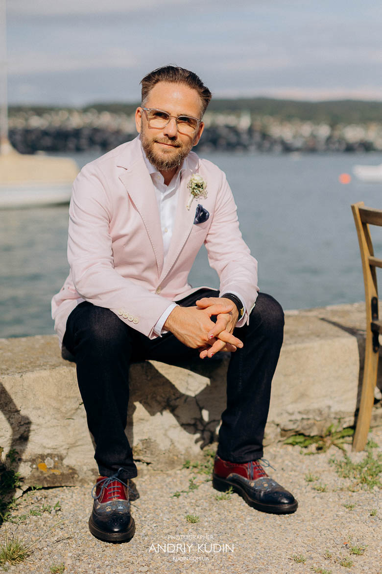 Bräutigam im rosa Sakko lächelt glücklich während seiner Hochzeit am Zürichsee in Zürich Schweiz