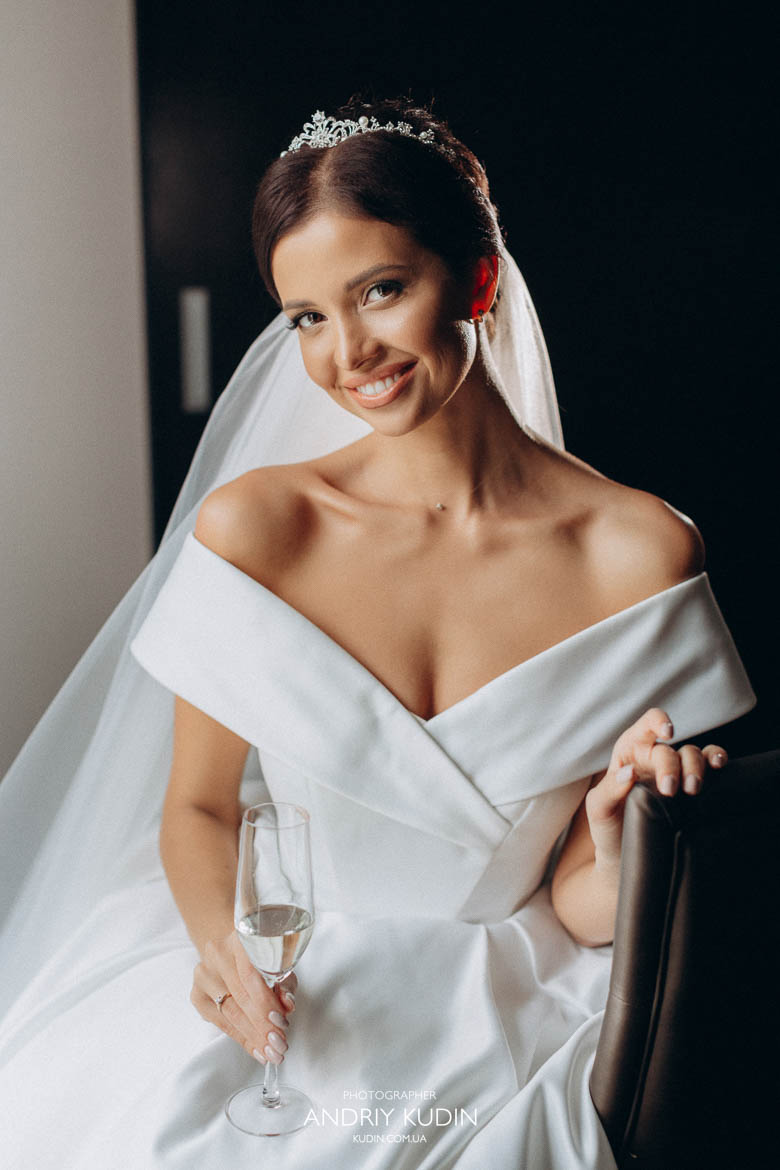 Braut lächelt während des Getting Ready Zürich. Braut im Fensterlicht im Hotelzimmer Zürich