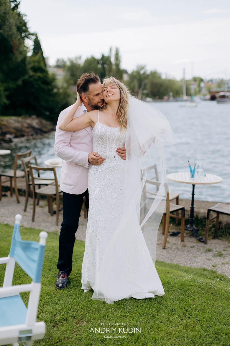 Romantische Umarmung eines Brautpaares bei einer Hochzeit in Zürich, Brautpaar küsst sich bei Sonnenuntergang am Zürichsee während Hochzeit