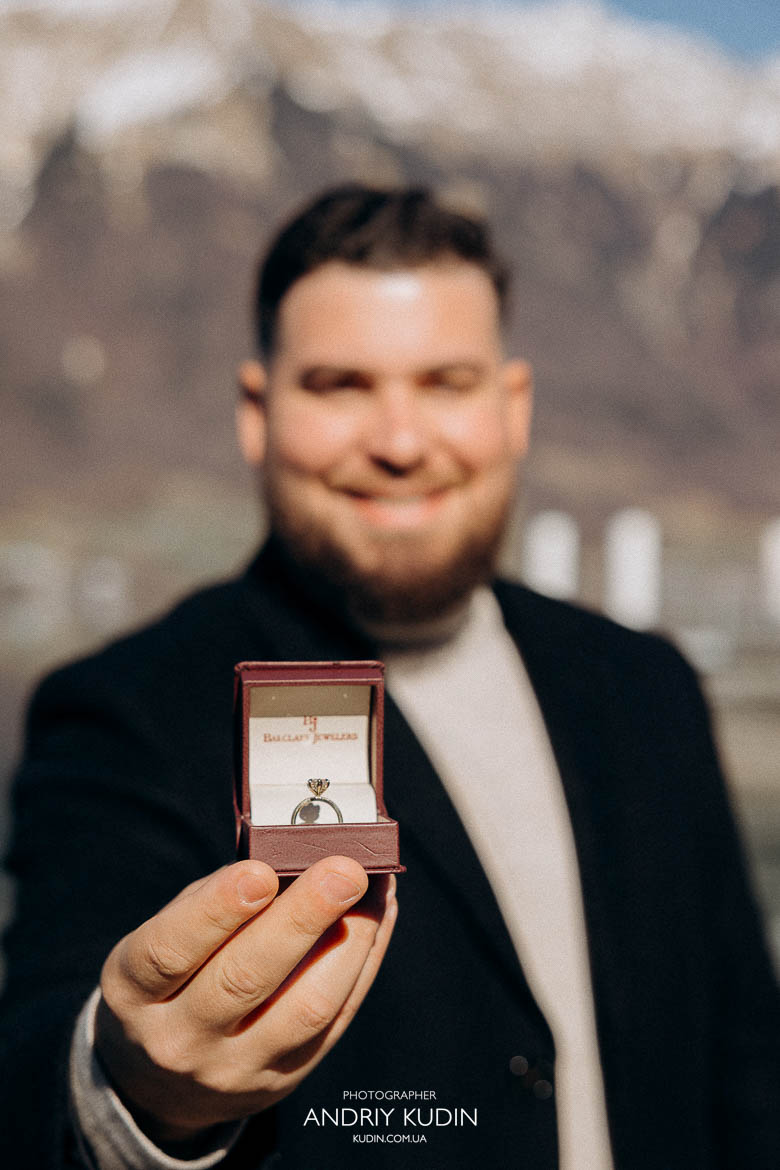 Close-up of engagement ring during proposal in Iseltwald, turquoise water background, 브리엔츠 호수 반지 디테일