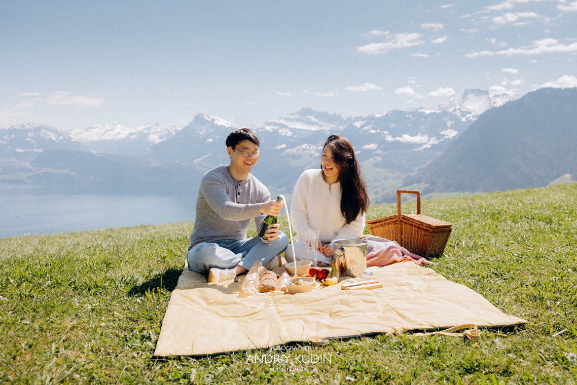 Couple enjoying romantic picnic in Swiss Alps at Villa Honegg Luxury apero experience with lake and mountain view Switzerland