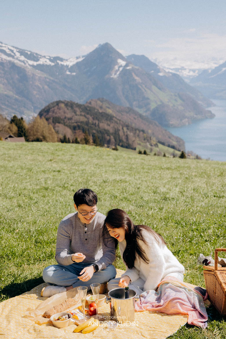 Couple sitting near apero setup with scenic Swiss landscape