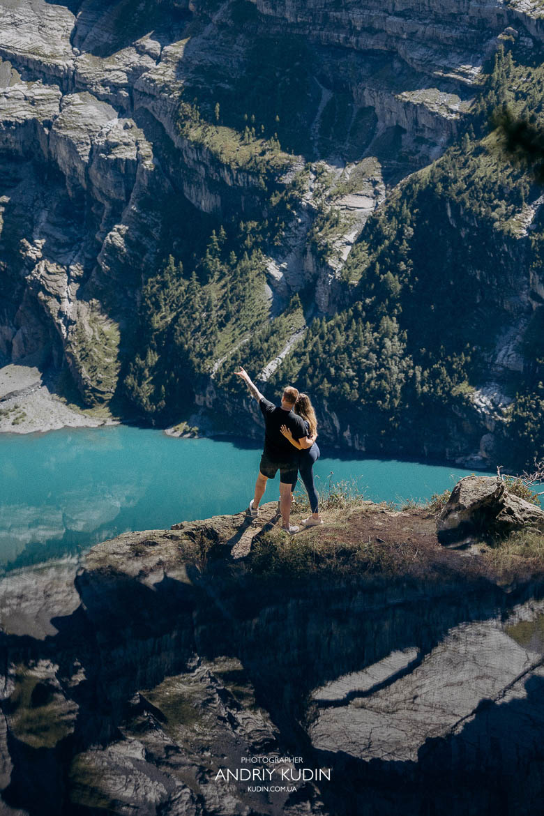 ouple standing near cliff above Lake Oeschinensee during proposal