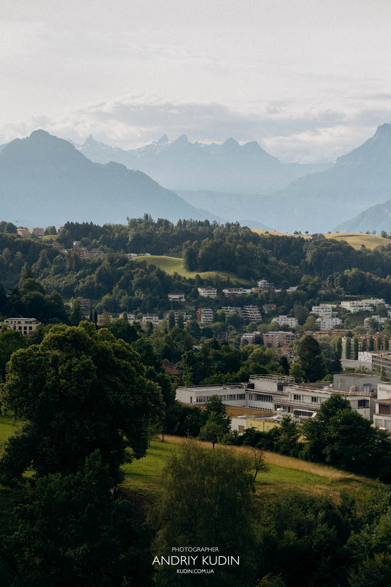 Shimmering waters of Lake Lucerne viewed from a peaceful, empty hilltop terrace. Golden morning light hitting the peaks of Mount Rigi during a Swiss engagement session. Shimmering waters of Lake Lucerne viewed from a peaceful, empty hilltop terrace. Golden morning light hitting the peaks of Mount Rigi during a Swiss engagement session.