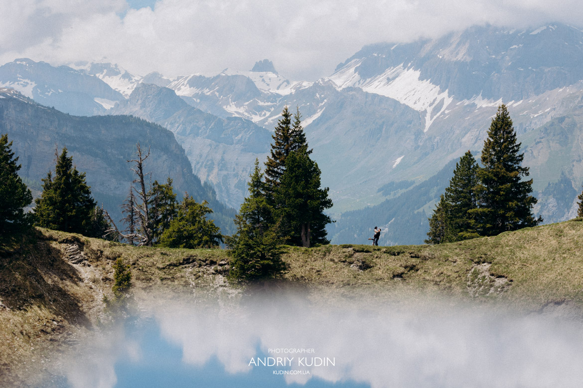 Romantic proposal Switzerland photography featuring a couple looking at the alpine scenery together.