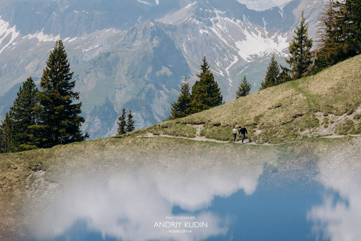 Alpine lake proposal Switzerland showcasing crystal clear blue water and mountains.
