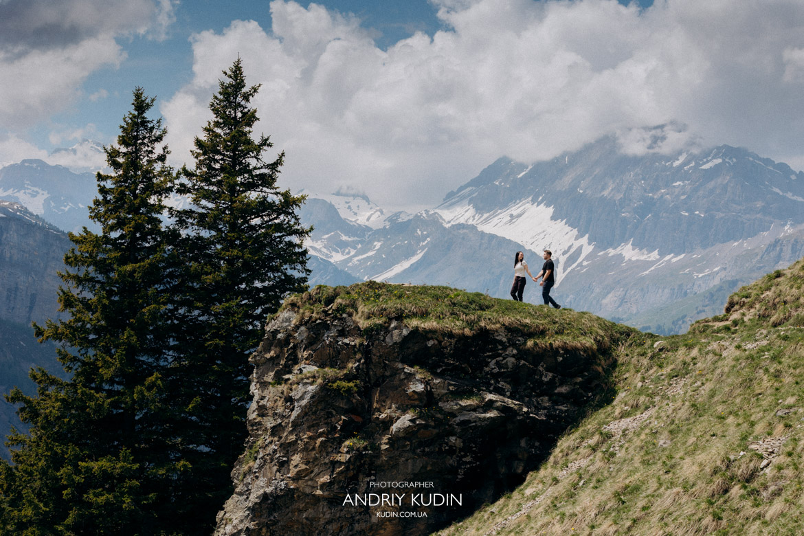 Loving couple standing together and gazing at the stunning mountains above Oeschinen Lake.