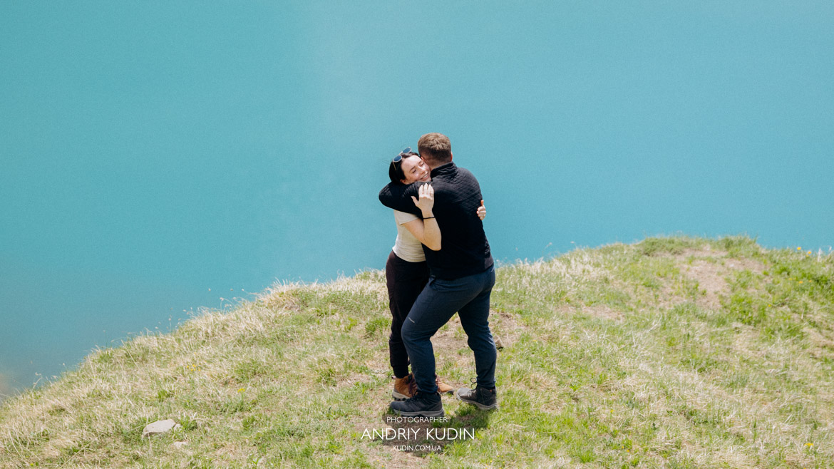 Alpine lake proposal Switzerland showcasing crystal clear blue water and mountains.