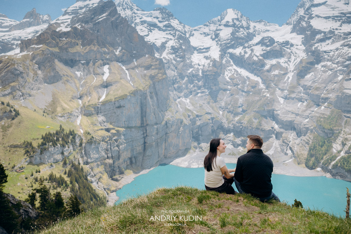 Surprise marriage proposal in Switzerland at Oeschinensee lake with snow-capped mountains.