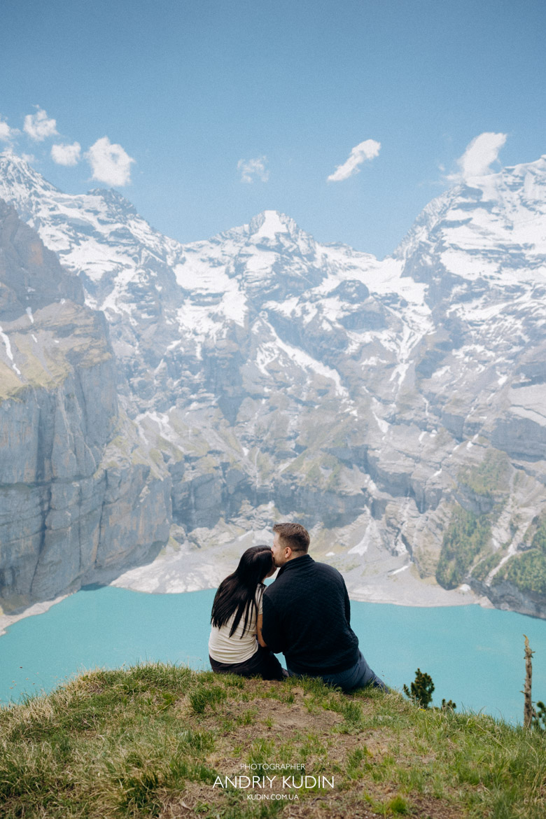 Romantic couple kissing by the turquoise water after an Oeschinensee proposal.