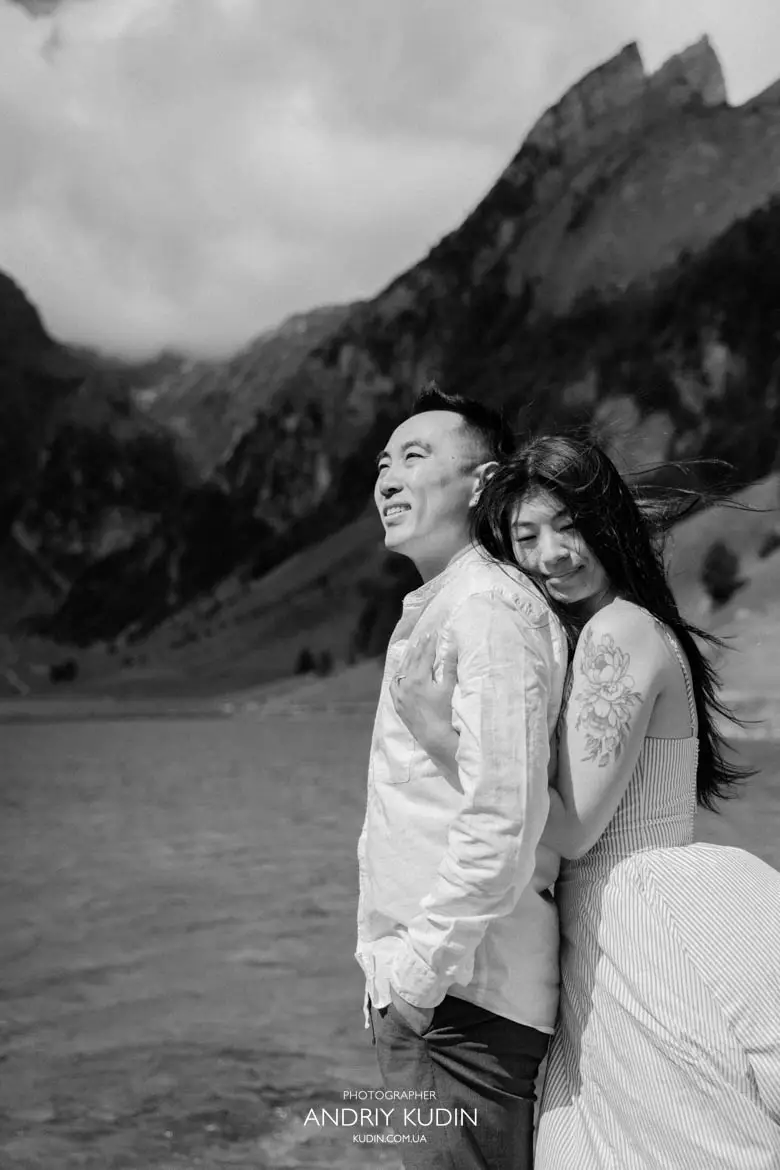 Black and white portrait of woman embracing fiancé from behind during Seealpsee engagement session