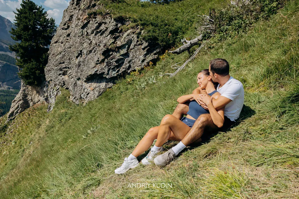 Couple embracing at the iconic two pine trees viewpoint over turquoise Lake Oeschinensee by Switzerland proposal photographer