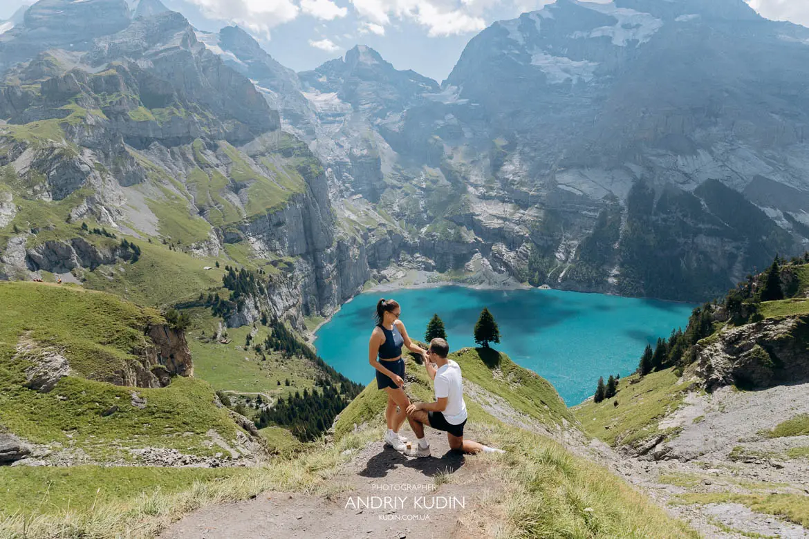 Holden down on one knee asking Misha to marry him overlooking Oeschinensee