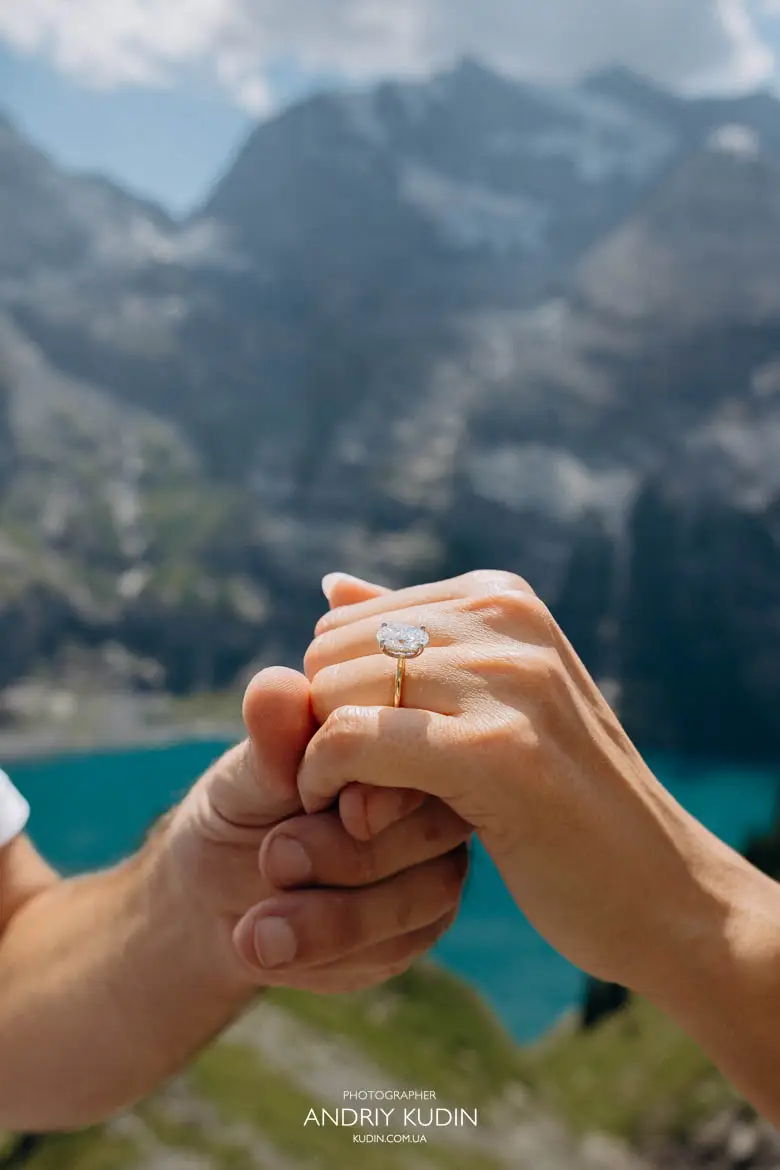 Close up of diamond engagement ring with blue Lake Oeschinensee captured by Switzerland proposal photographer