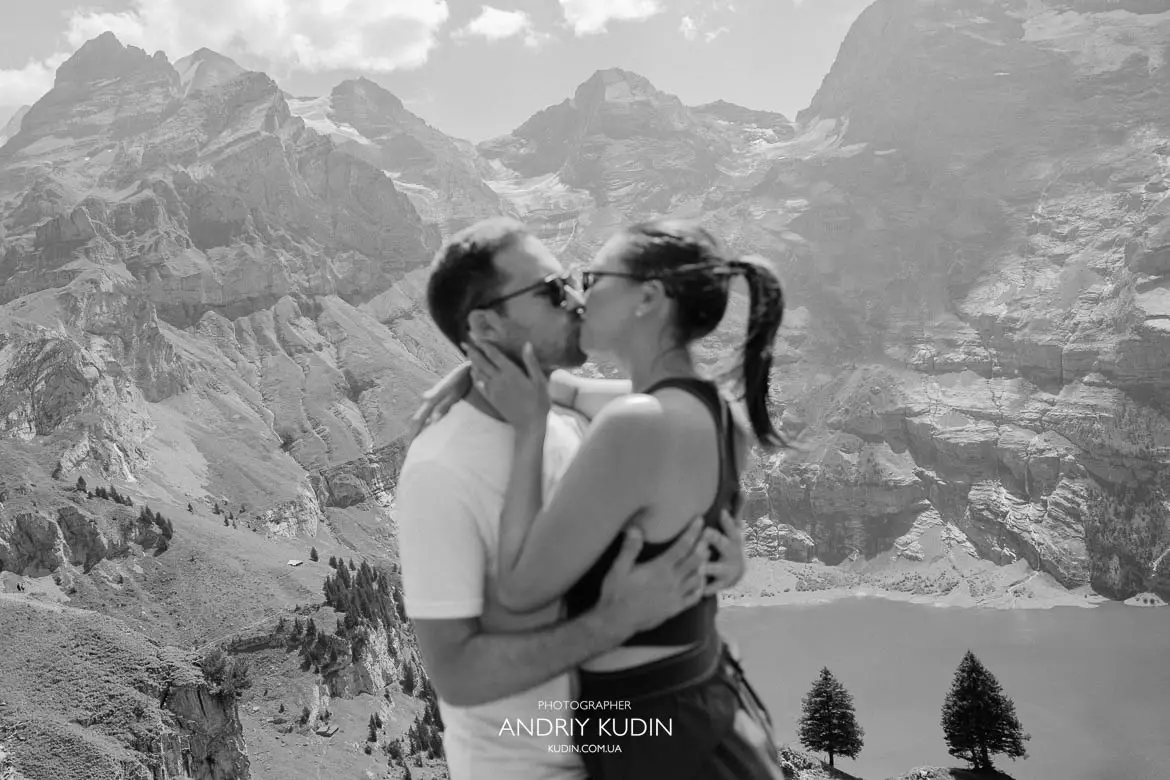 Black and white emotional kiss after marriage proposal at Heuberg viewpoint above Lake Oeschinensee