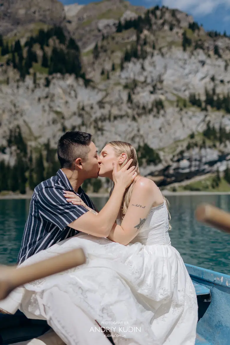 Romantic emotional kiss of happy engaged couple sitting in a blue rowboat on Lake Oeschinen Switzerland