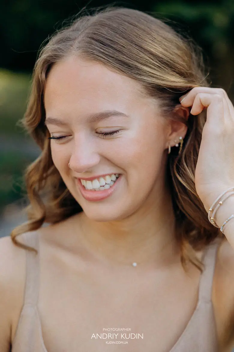 Close up portrait of smiling young woman holding her hair during family photoshoot in Switzerland