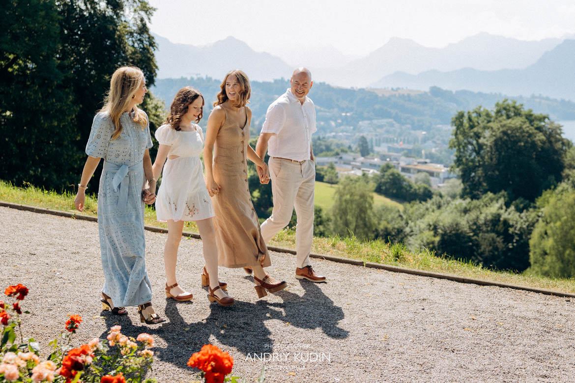 Happy family holding hands and walking together along gravel path with Swiss mountains view