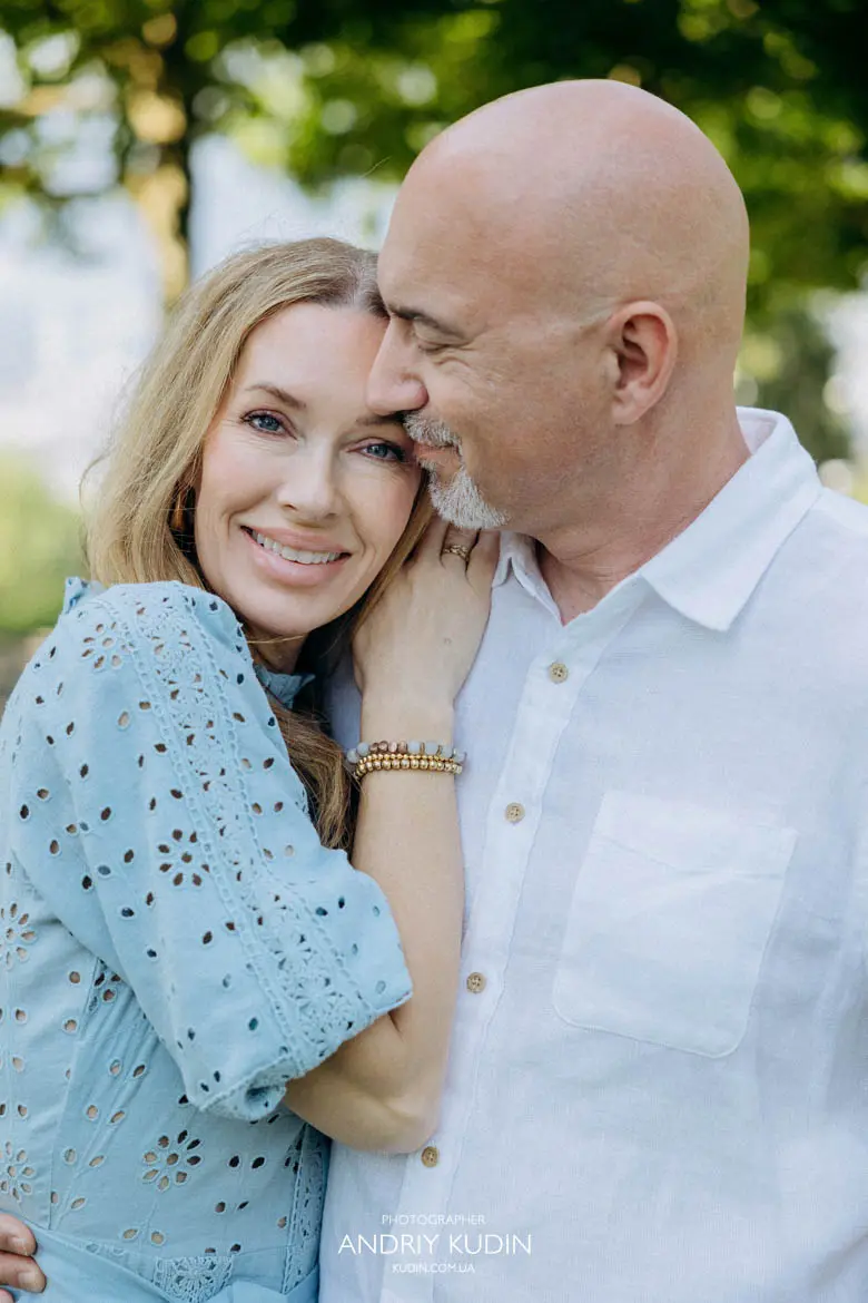 Beautiful blonde woman smiling while leaning on her husband during couple photoshoot in Swiss park