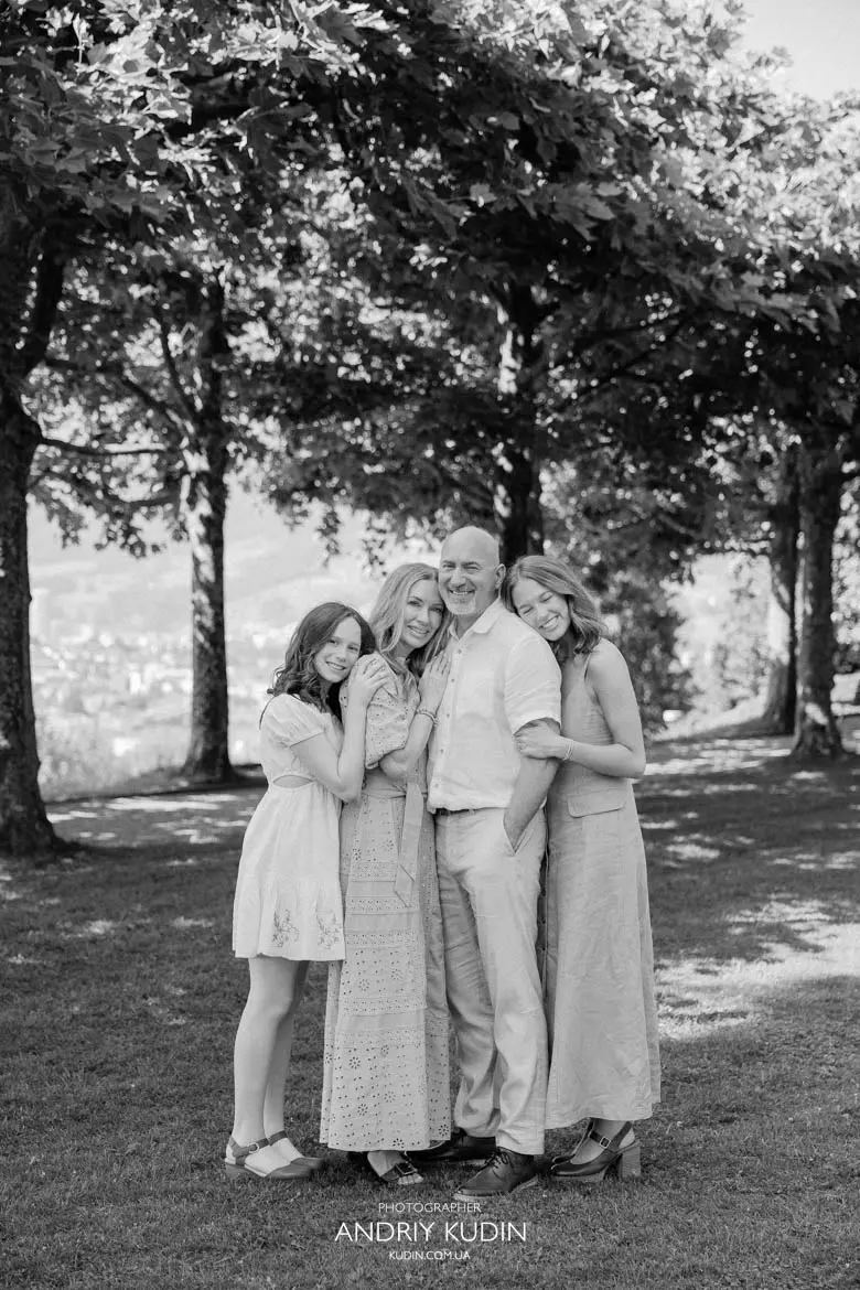 Full length black and white photo of happy family with grown up daughters posing in Swiss park