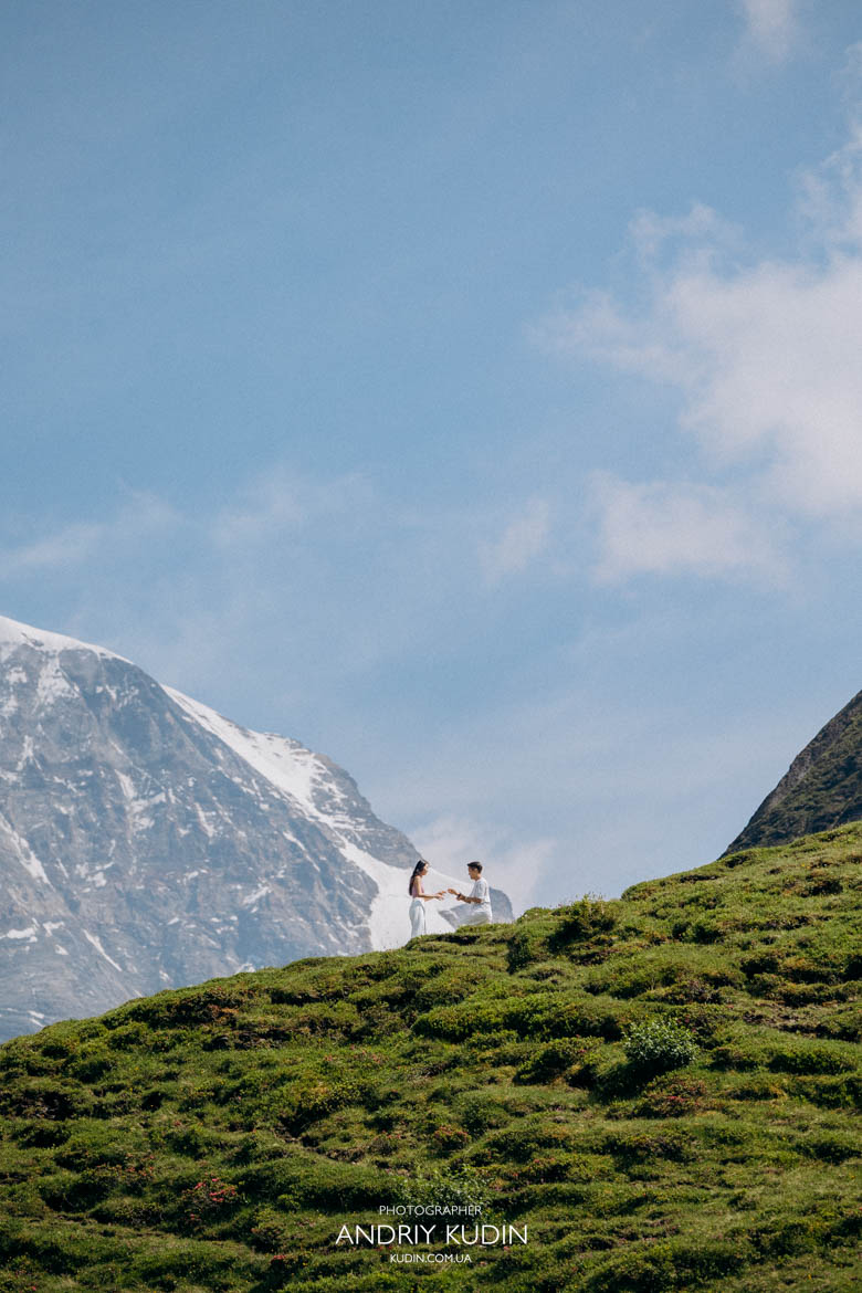 Man on one knee at Männlichen Romantic surprise proposal in the Swiss Alps man on one knee in front of snow-capped mountain by switzerland proposal photographer