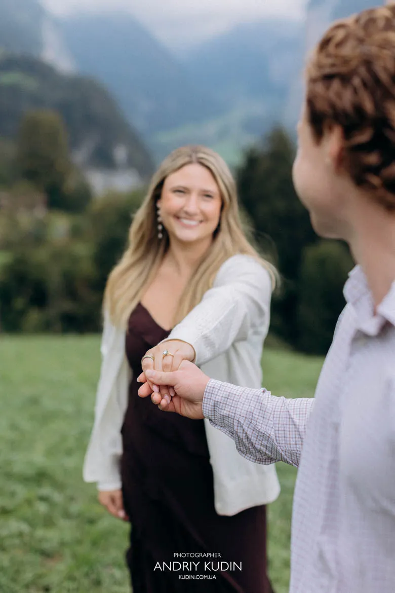 Smiling bride-to-be holding hands with partner showing engagement ring in Lauterbrunnen. Photo by switzerland proposal photographer.