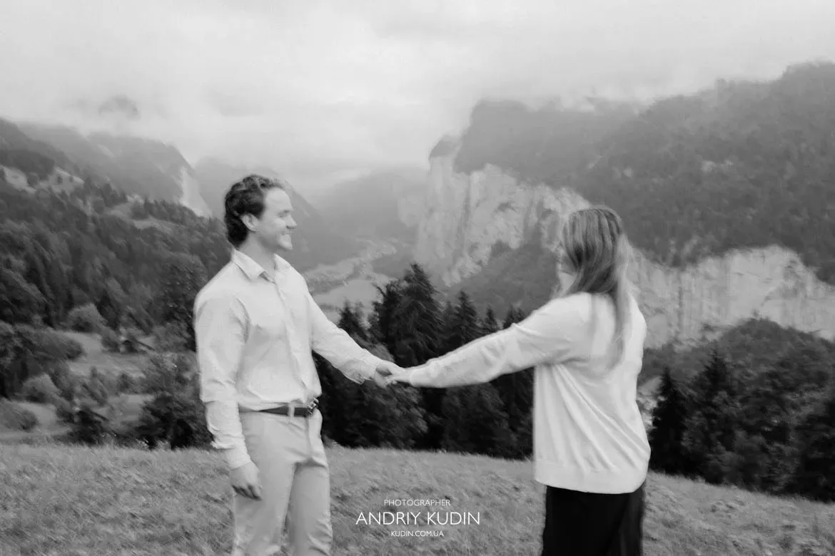 Romantic moment of Austin and Elizabeth walking hand in hand through misty Lauterbrunnen Valley.