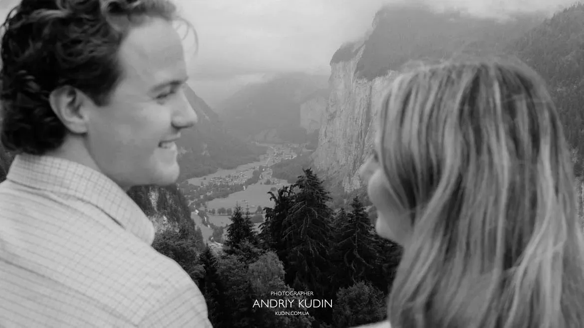 Black and white portrait of smiling couple looking at each other overlooking Lauterbrunnen Valley. Photo by switzerland proposal photographer.